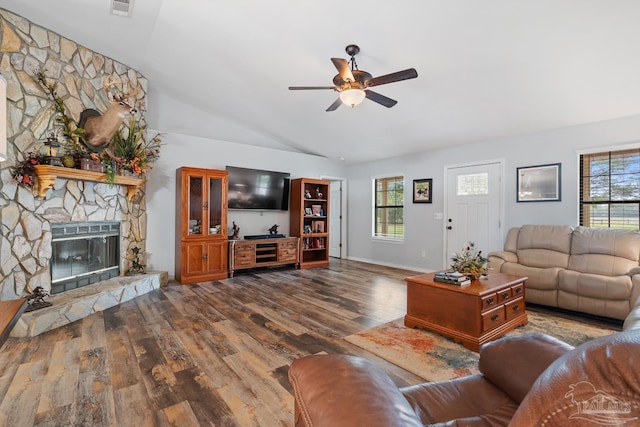 living room with a ceiling fan, a stone fireplace, lofted ceiling, and wood finished floors