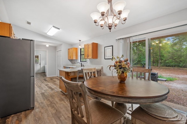 dining area featuring light wood finished floors, vaulted ceiling, visible vents, and an inviting chandelier