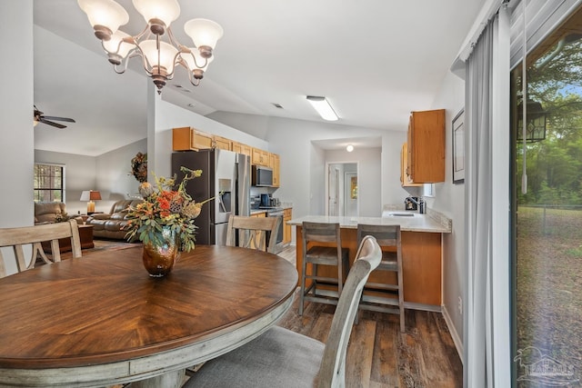 dining room featuring dark wood-style flooring, ceiling fan with notable chandelier, and lofted ceiling