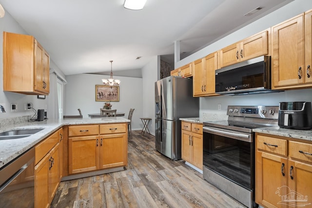kitchen with a peninsula, appliances with stainless steel finishes, lofted ceiling, a sink, and light wood-type flooring