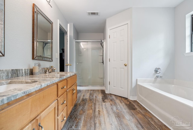 bathroom with a stall shower, a sink, a garden tub, wood finished floors, and visible vents