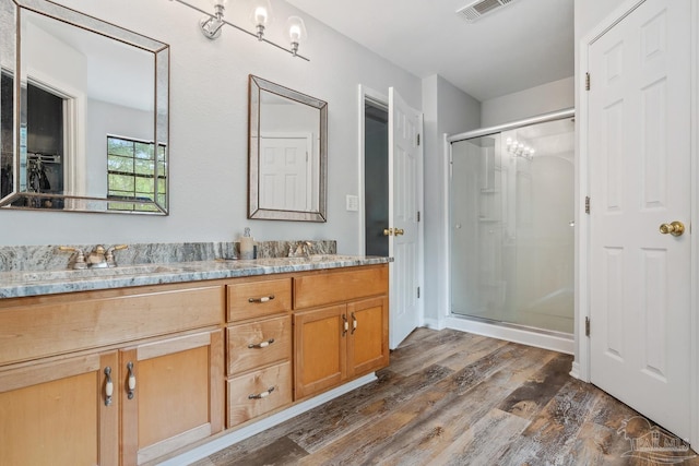 full bathroom with a sink, visible vents, a shower stall, and wood finished floors