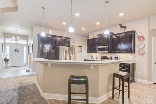 kitchen with appliances with stainless steel finishes, sink, dark brown cabinets, and decorative light fixtures