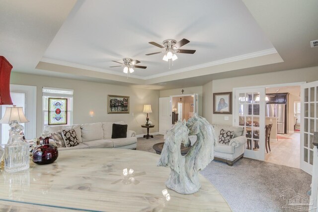 carpeted living room with a raised ceiling and ornamental molding