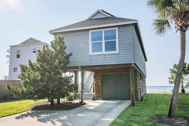 view of front of house with a garage, a front lawn, and a water view