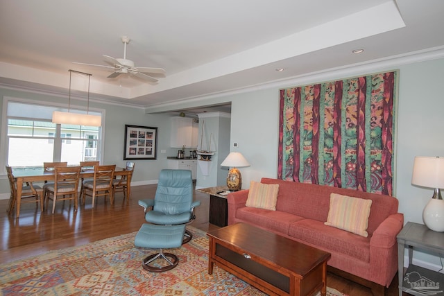 living room with ceiling fan, hardwood / wood-style flooring, ornamental molding, and a raised ceiling