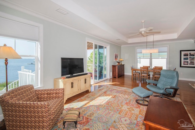 living room with hardwood / wood-style floors, crown molding, a tray ceiling, and ceiling fan