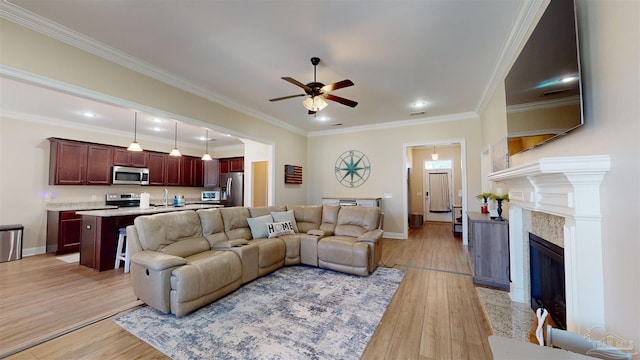 living room with light hardwood / wood-style floors, ceiling fan, crown molding, and sink