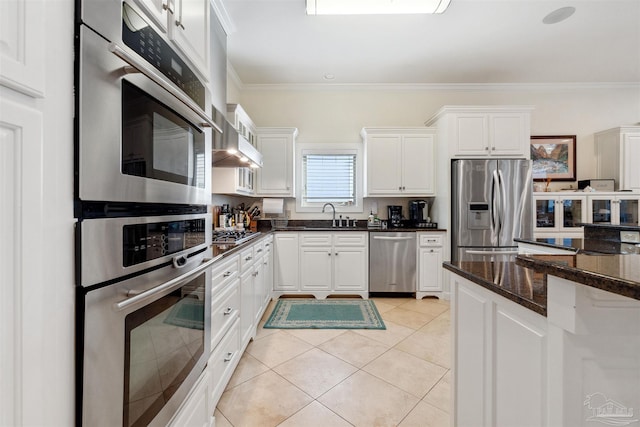 kitchen featuring dark stone countertops, appliances with stainless steel finishes, light tile patterned floors, and white cabinetry