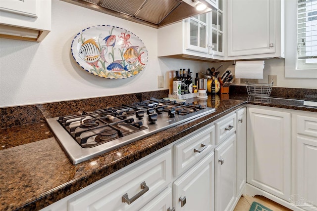 kitchen featuring dark stone counters, white cabinetry, stainless steel gas cooktop, and custom range hood