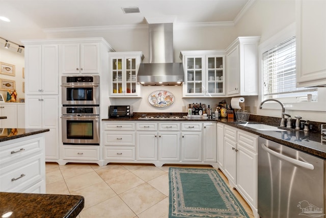 kitchen featuring wall chimney exhaust hood, white cabinetry, appliances with stainless steel finishes, and dark stone counters