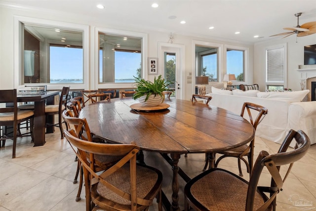 tiled dining area featuring ceiling fan and crown molding