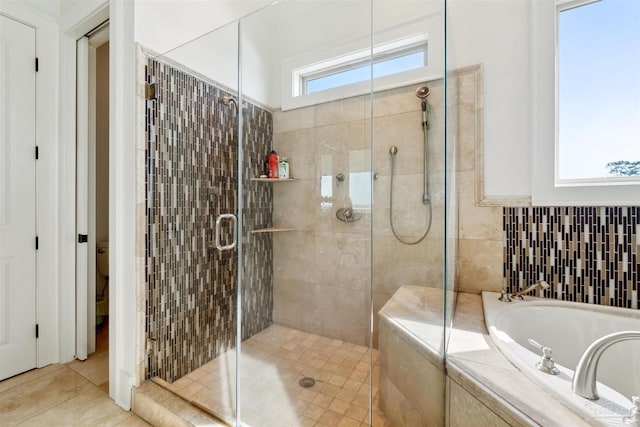 bathroom featuring plus walk in shower, tile patterned floors, toilet, and a wealth of natural light