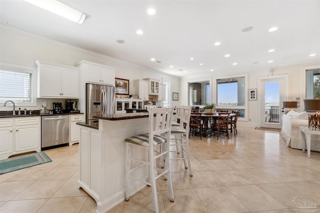 kitchen with a kitchen island, a healthy amount of sunlight, white cabinetry, and stainless steel appliances