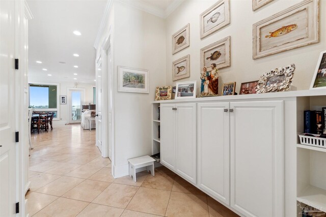 hall featuring light tile patterned floors and crown molding