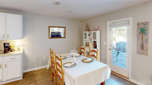 dining room with dark wood finished floors, visible vents, and baseboards