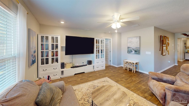 living area featuring baseboards, a ceiling fan, and wood finished floors