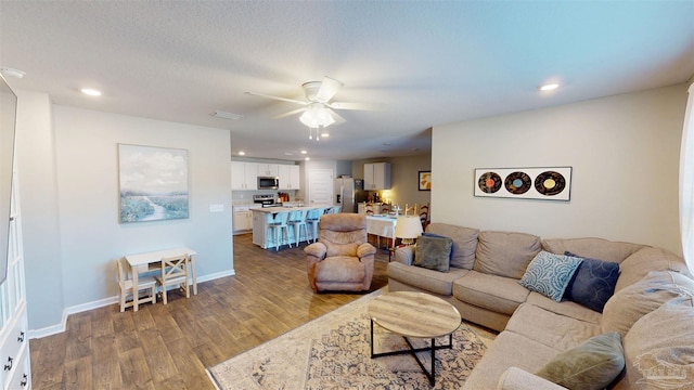 living room with ceiling fan, recessed lighting, wood finished floors, and baseboards