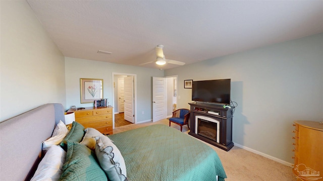 bedroom with ceiling fan, a fireplace, baseboards, and light colored carpet