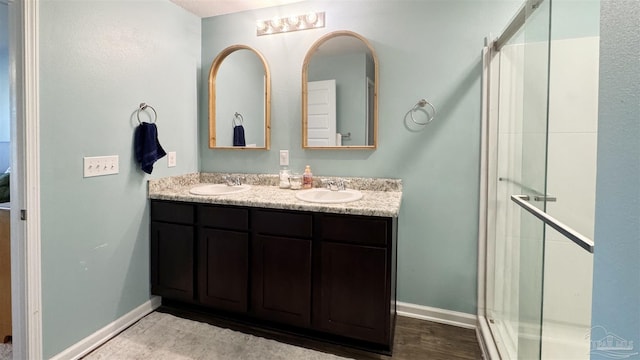 bathroom featuring baseboards, a sink, and a shower stall