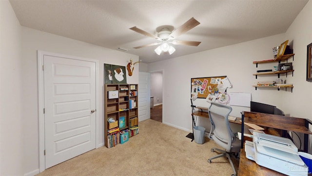 home office with light colored carpet, ceiling fan, visible vents, and baseboards