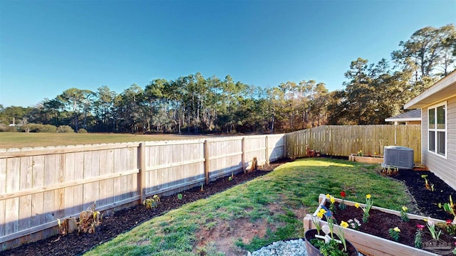 view of yard featuring a garden, central AC, and a fenced backyard