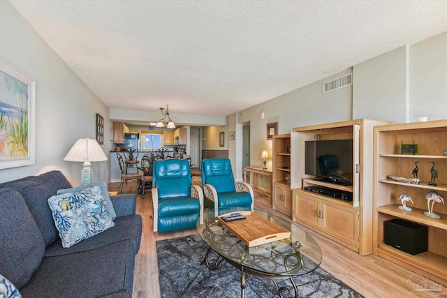 living room with a textured ceiling, visible vents, and light wood-type flooring