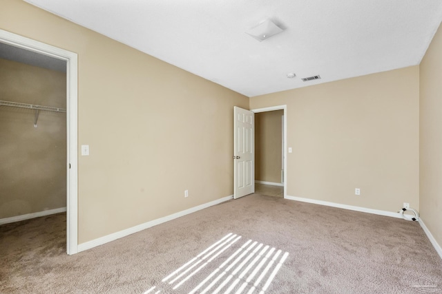 unfurnished bedroom featuring light carpet, a spacious closet, and a closet