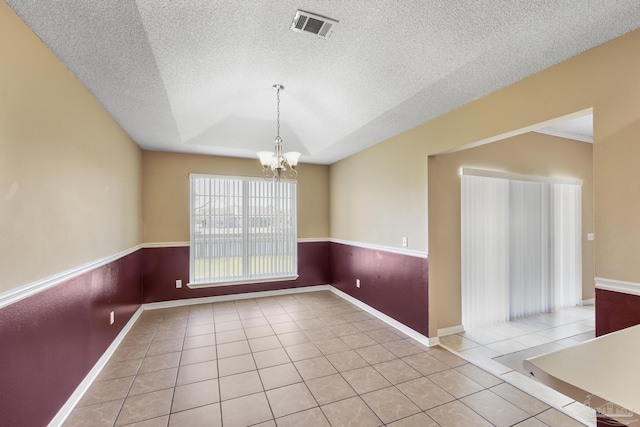 unfurnished room featuring light tile patterned flooring, a textured ceiling, and an inviting chandelier