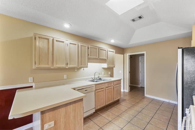 kitchen featuring stainless steel fridge, a skylight, white dishwasher, a tray ceiling, and sink