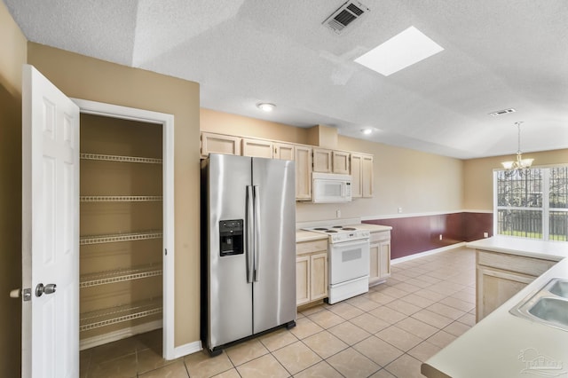 kitchen with white appliances, hanging light fixtures, light brown cabinetry, a notable chandelier, and light tile patterned flooring