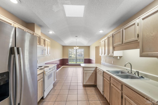 kitchen featuring a skylight, sink, kitchen peninsula, pendant lighting, and white appliances