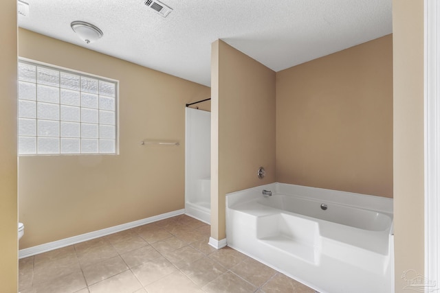 bathroom with tile patterned floors, separate shower and tub, toilet, and a textured ceiling