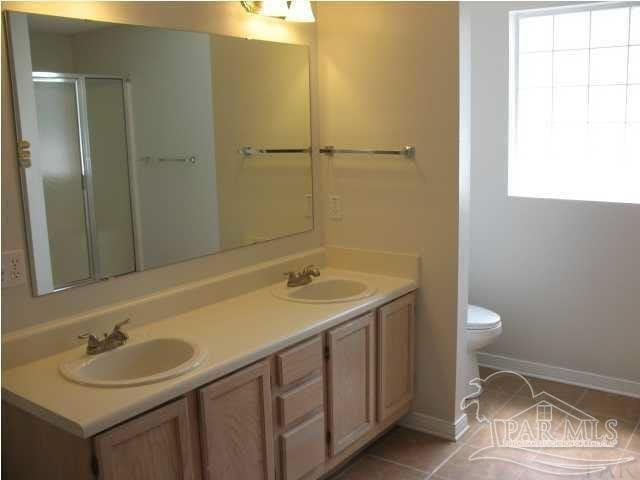 bathroom featuring tile patterned flooring, vanity, toilet, and an enclosed shower