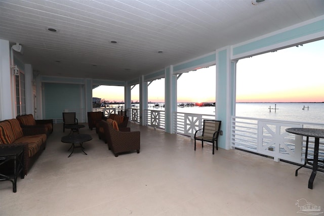 patio terrace at dusk with an outdoor living space and a water view