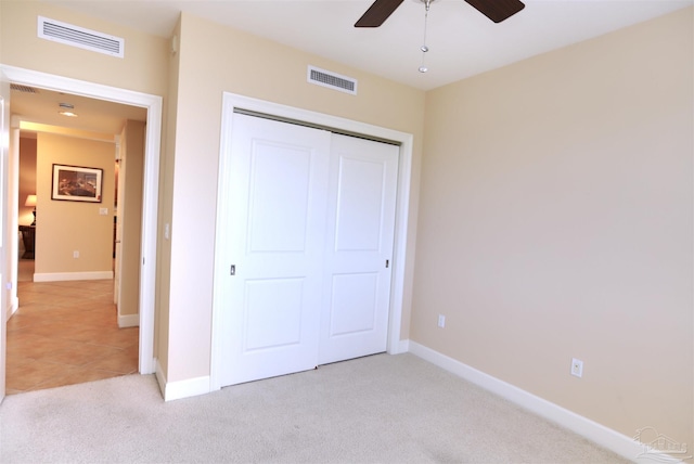 unfurnished bedroom with ceiling fan, light carpet, and a closet