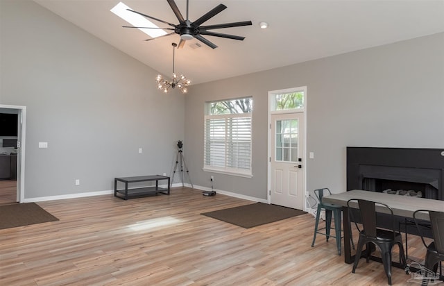 interior space featuring ceiling fan with notable chandelier, light wood-type flooring, and high vaulted ceiling