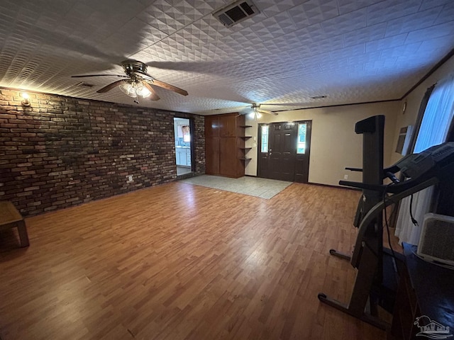 6232 Jalyn Rd, Pensacola, FL 32503 - unfurnished living room featuring visible vents, brick wall, light wood-style flooring, and a ceiling fan
