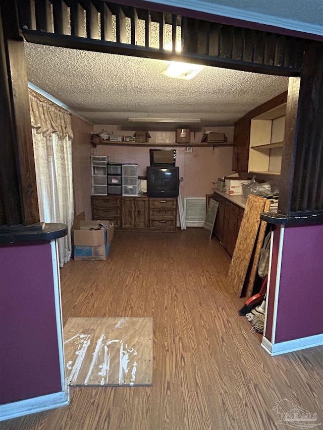 6232 Jalyn Rd, Pensacola, FL 32503 - kitchen with baseboards, light wood-style flooring, a textured ceiling, and a peninsula