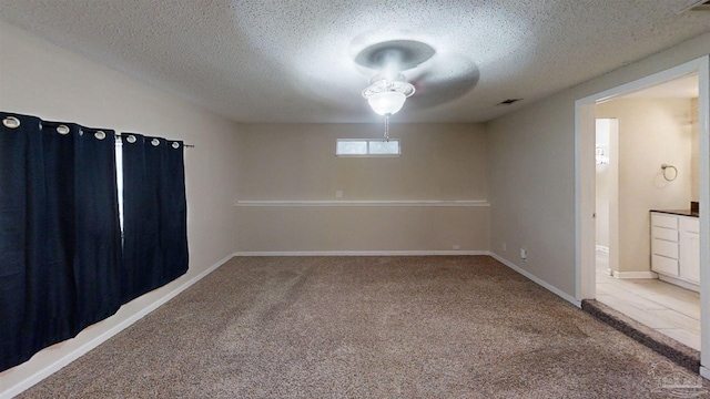 carpeted empty room featuring ceiling fan and a textured ceiling