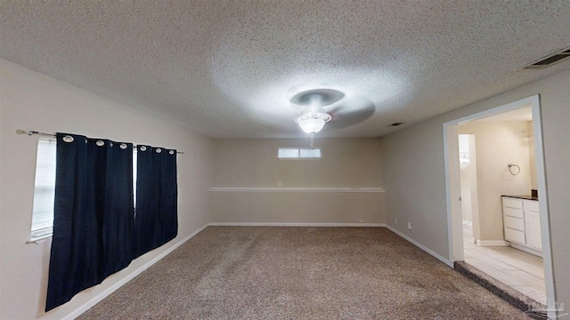 carpeted spare room with a textured ceiling and ceiling fan