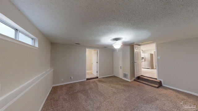 interior space featuring stainless steel refrigerator with ice dispenser, a textured ceiling, connected bathroom, and carpet floors