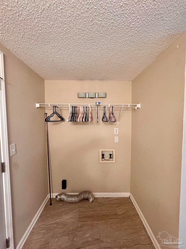 washroom with hookup for a washing machine and a textured ceiling