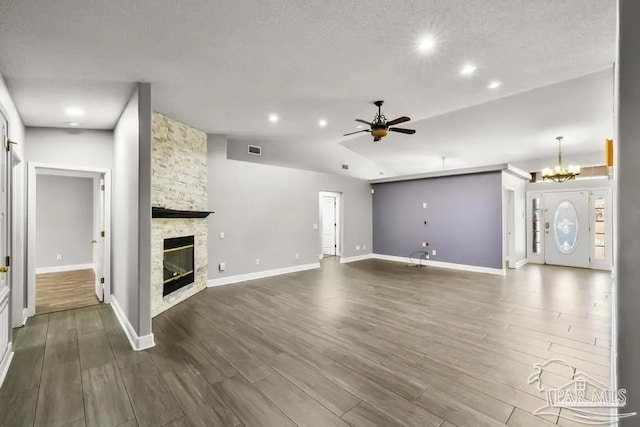 7210 Annandale Dr, Pensacola, FL 32526 - unfurnished living room with lofted ceiling, ceiling fan with notable chandelier, a textured ceiling, a fireplace, and wood-type flooring