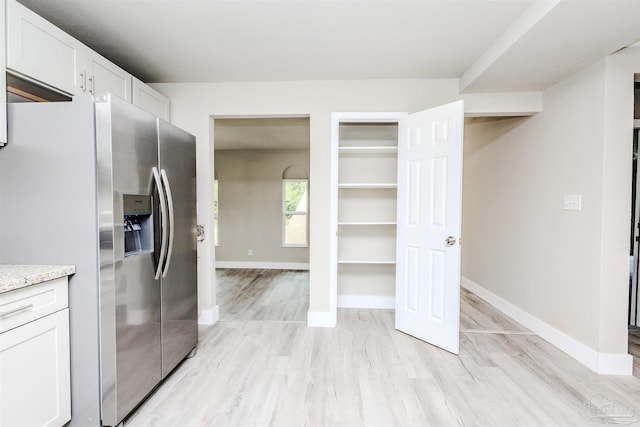 kitchen featuring light wood-style flooring, white cabinets, baseboards, and stainless steel refrigerator with ice dispenser