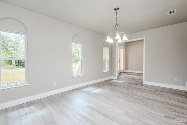 unfurnished room with a wealth of natural light, visible vents, wood finished floors, and a chandelier