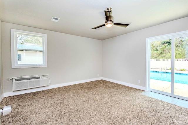 spare room with visible vents, baseboards, ceiling fan, a wall mounted air conditioner, and carpet floors