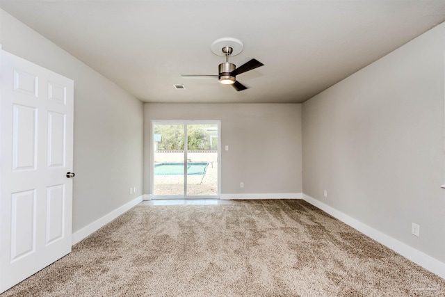 carpeted spare room with visible vents, a ceiling fan, and baseboards