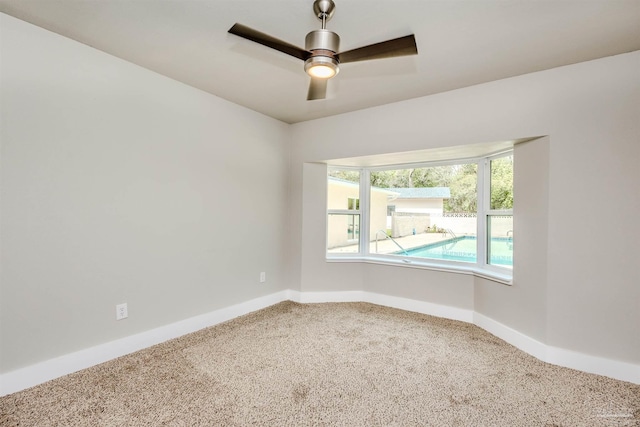 carpeted empty room with baseboards and ceiling fan