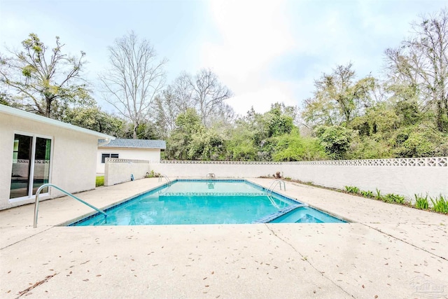 view of pool with a patio, fence, and a pool with connected hot tub